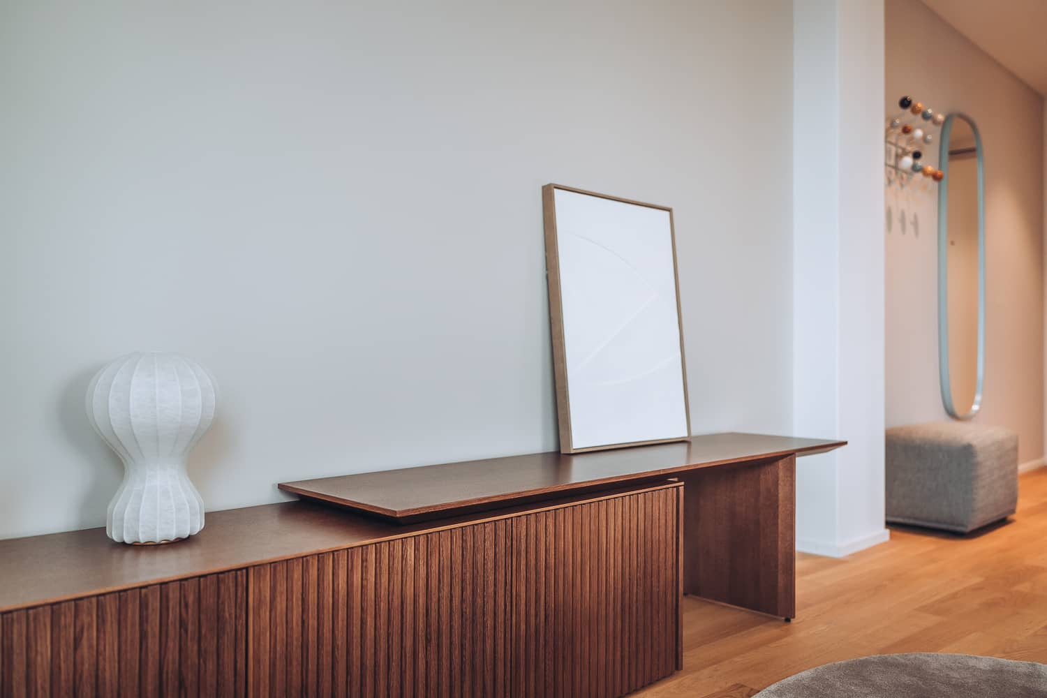 Auf einem langen h&ouml;lzernen Sideboard stehen eine stimmungsvolle Lampe und ein grosses Bild